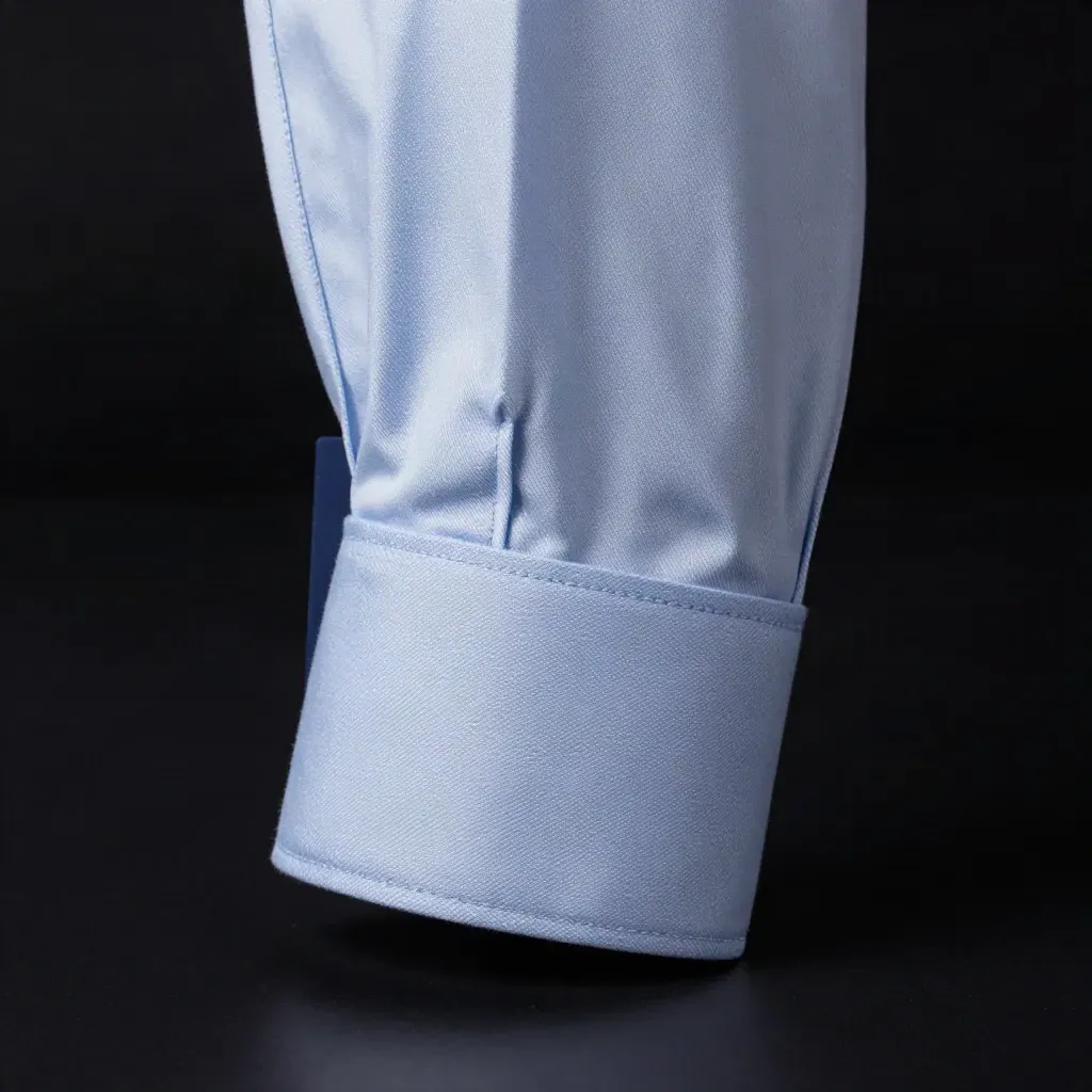Manga de camisa azul-clara com barra ajustada, punho dobrado e toque de movimento.